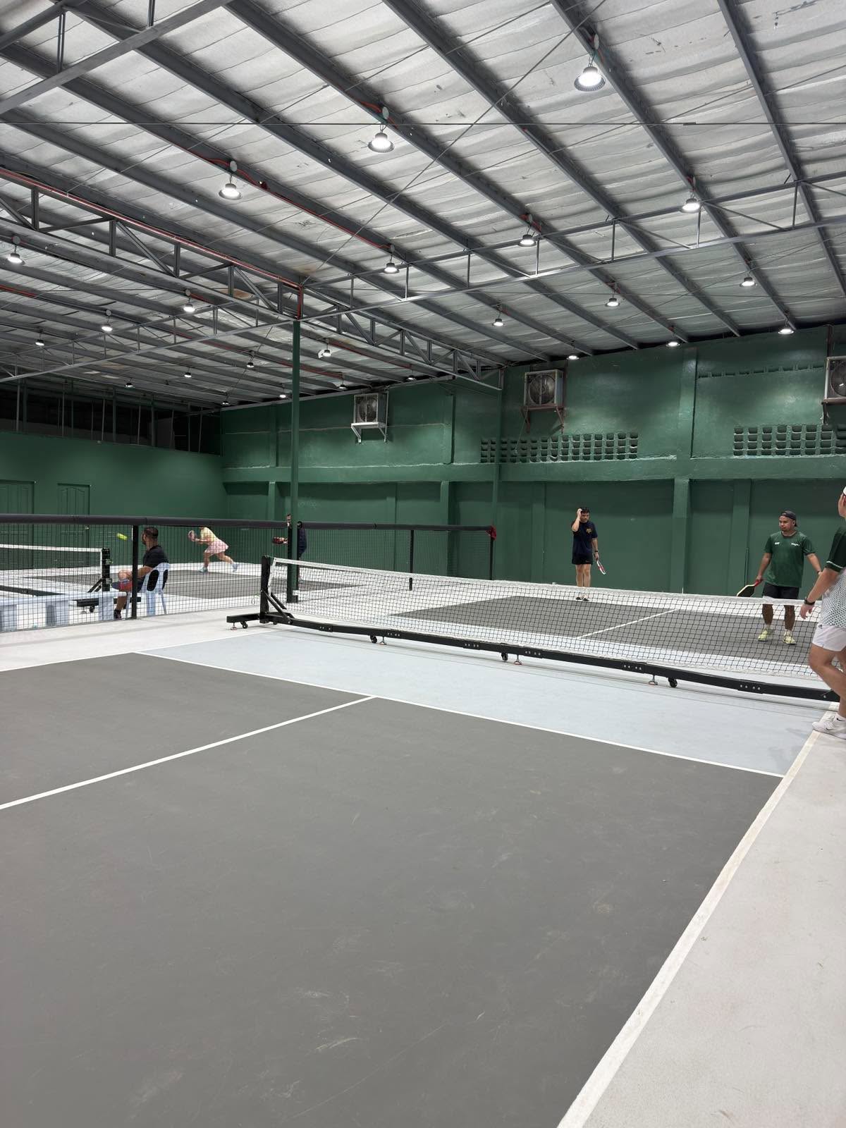 A corner view of an indoor pickleball court with games on the neighbouring courts