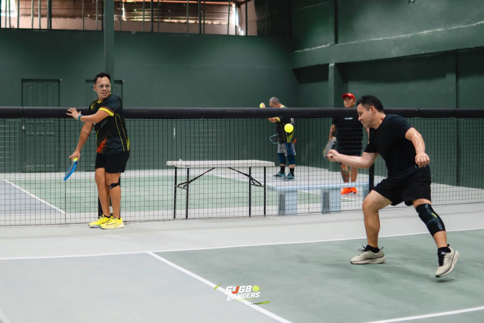 Pickleball players competing in a rally at Hoops & Racket